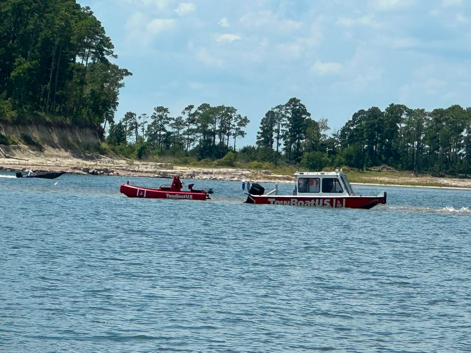 Two service boats moored on Sam Rayburn Reservoir, forested shoreline and clear sky behind them.